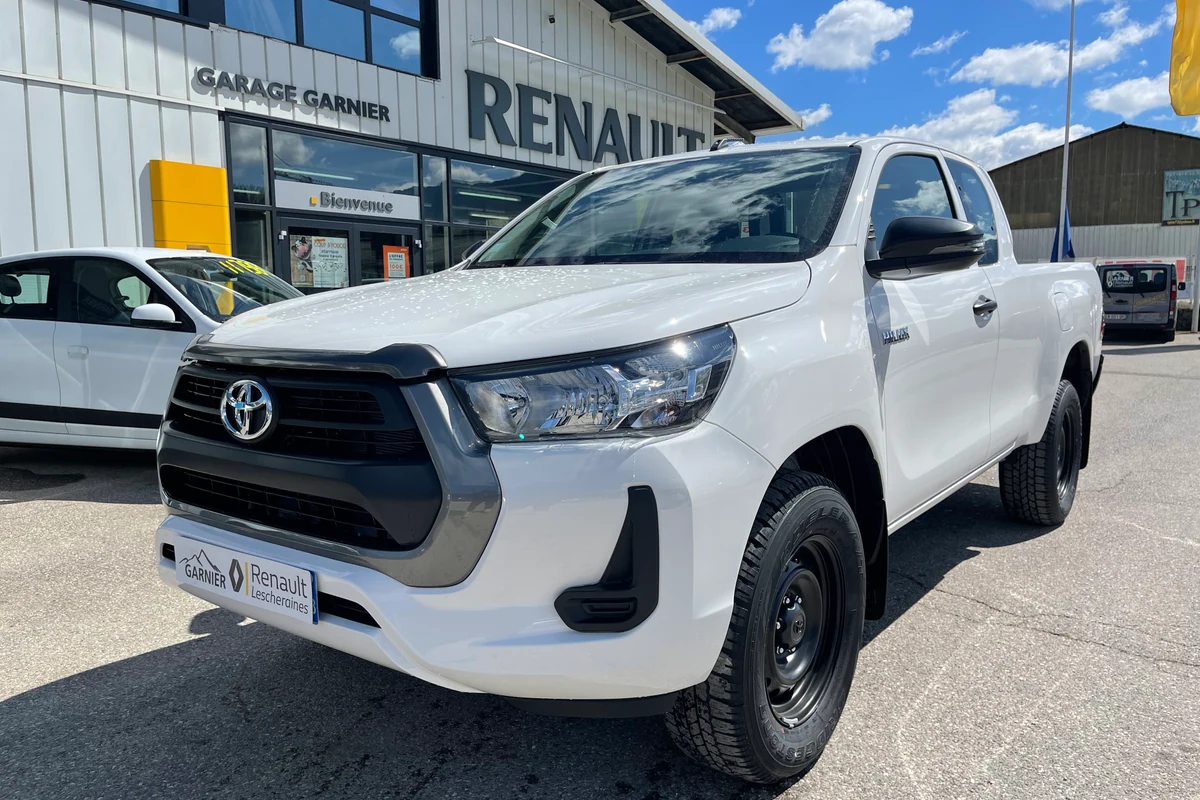 Un pick-up Hilux blanc avec attelage, sur le parvis
