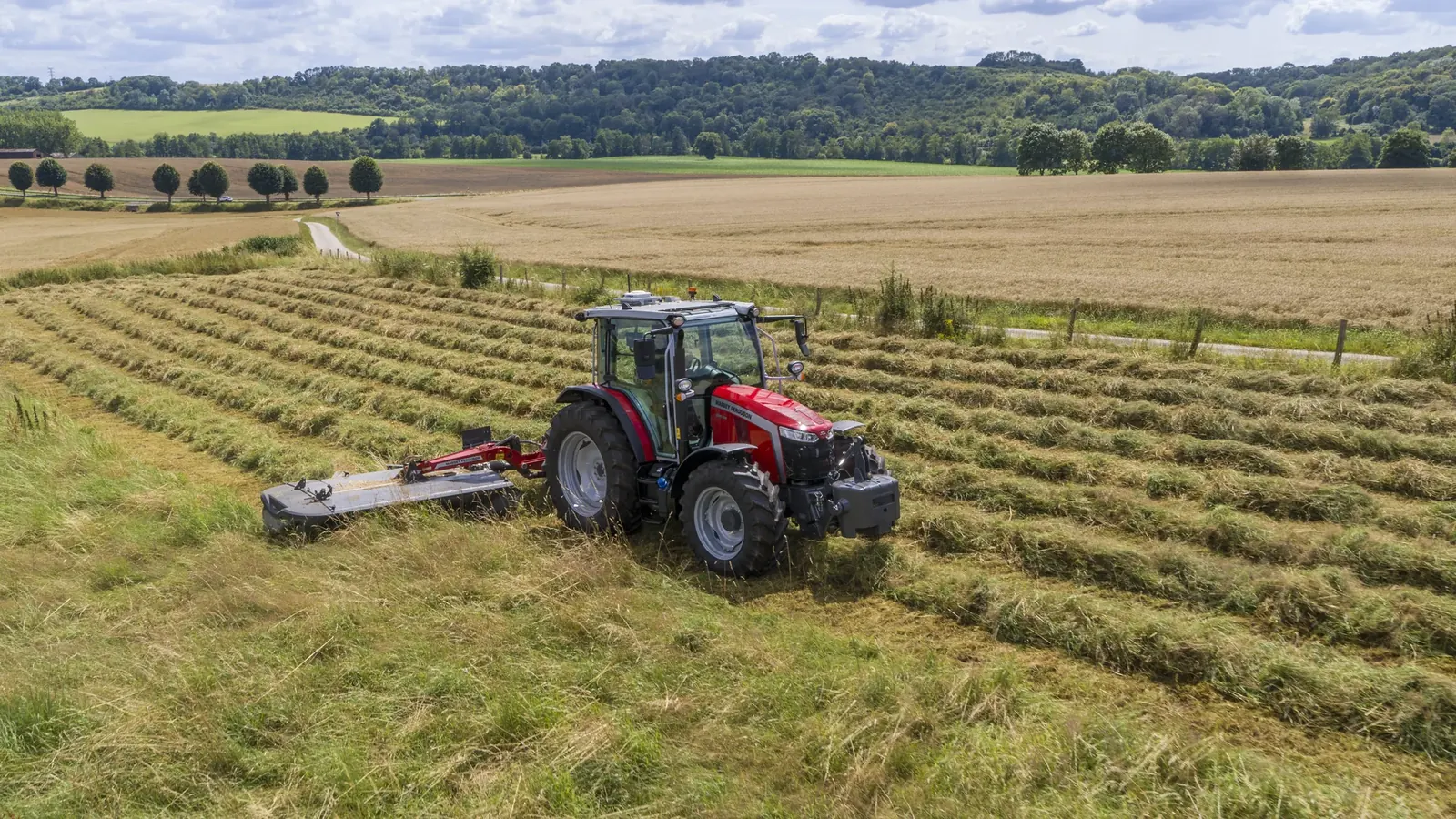 Un tracteur Massey Ferguson 5M fauche une prairie, vu du ciel