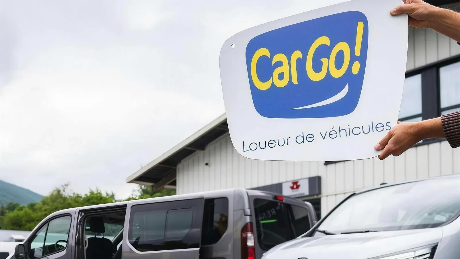 L'enseigne de location posée sur la façade, devant deux utilitaires Renault