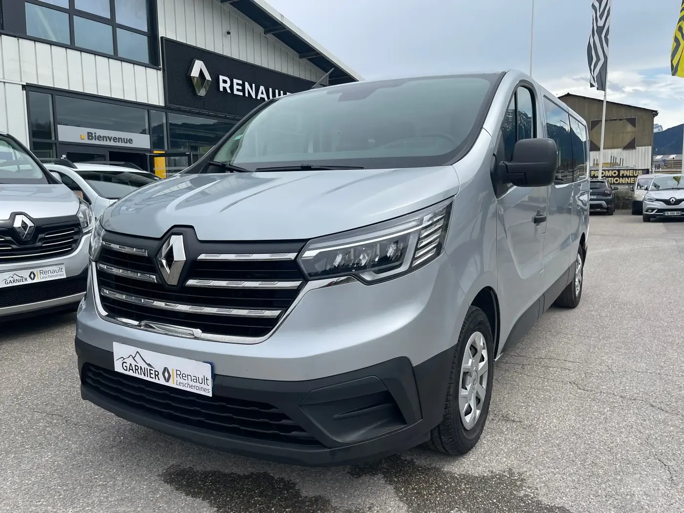 Un minibus neuf places gris devant la vitrine